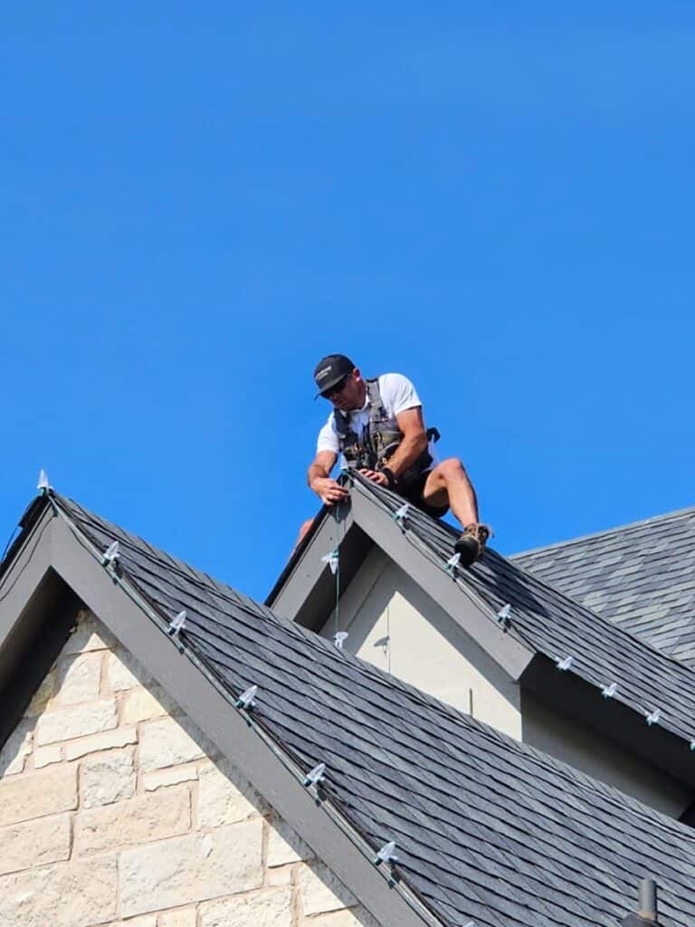 Person installing lights on rooftop.